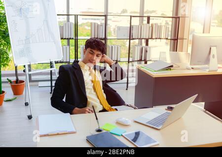 A young businessman is sitting down for a short break from hard work throughout his work hours to relieve stress and create new ideas from working in Stock Photo