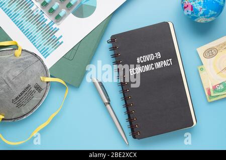 COVID-19 or Corona virus Economic IMPACT background concept. Mockup Notebook for Covid 19 Economic impact anlysis with busines graphs sheets, N95 faci Stock Photo