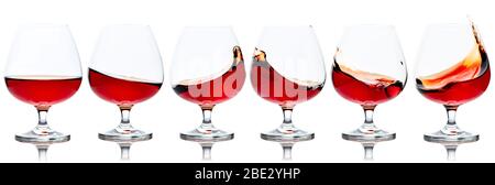 Set of brandy snifters with cognac splashes. Splashes of cognac in glasses, isolated on white background. Stock Photo
