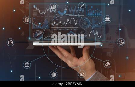 Hand holds tablet with graphs and symbols Stock Photo