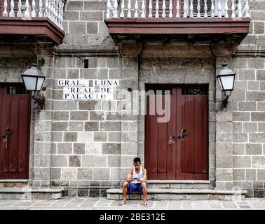 Local filipino sitting in front of a colonial house in Intramuros, Manila, Philippines Stock Photo