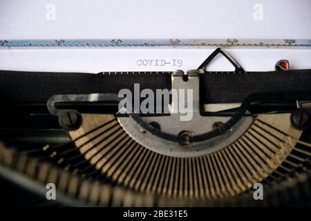 Inscription COVID-19 is printed on a white sheet with an old typewriter Stock Photo