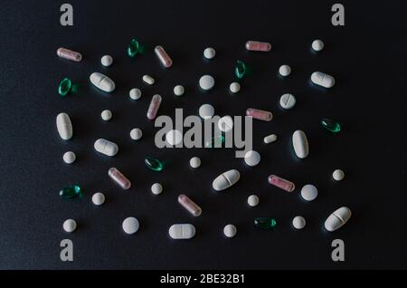 A lot of different pink, green and white coloured pills making mosaic on black matte background. Healthcare and medical concept. Horisontal frame, clo Stock Photo