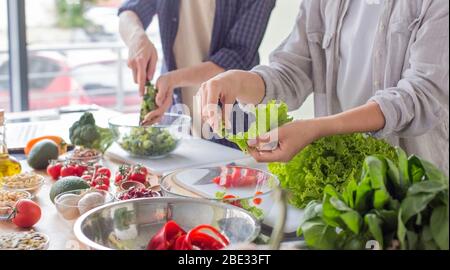 Millennial couple preparing healthy vegetarian salad enjoying process Stock Photo