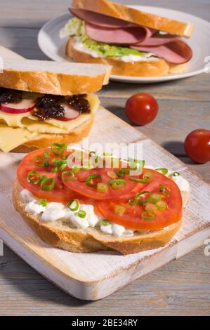 Varieties of meat and vegetarian sandwiches on a rustic cutting board. Stock Photo