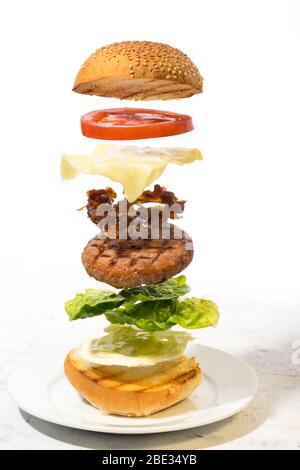 Burger preparation sliced  ingredients levitating on white background Stock Photo