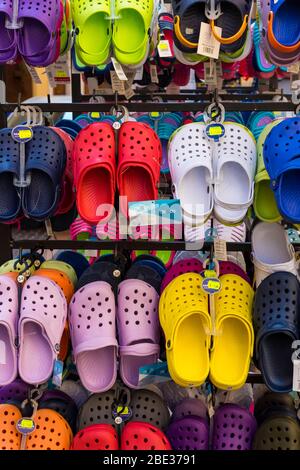 A colourful collection of plastic 'croc' type shoes for sale on an outdoor display rack, Italy. Stock Photo