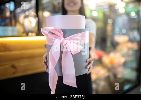Dark-haired female shop assistant holding a gift box Stock Photo