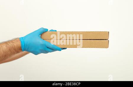 Pizza delivery. Men's hands in medical gloves hold pizza boxes. Service quarantine pandemic coronavirus flu 2019-ncov concept. Covid-19 Stock Photo