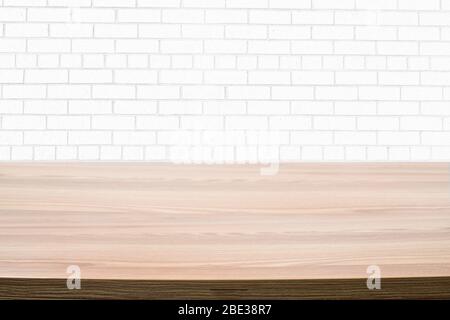 Photo of a light brown wooden table next to a white brick wall. Stock Photo