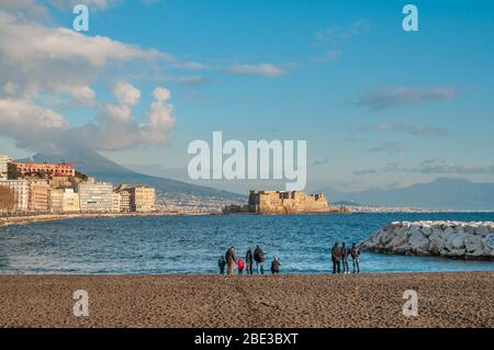 A group of people admire the Naples waterfront seen from a city beach. Stock Photo