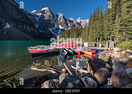 Colorful canoes docked in the turquoise waters of Lake Louise and the snow dusted Fairview Mountain behind in Banff National Park in Alberta, Canada. Stock Photo