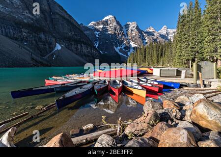 Colorful canoes docked in the turquoise waters of Lake Louise and the snow dusted Fairview Mountain behind in Banff National Park in Alberta, Canada. Stock Photo