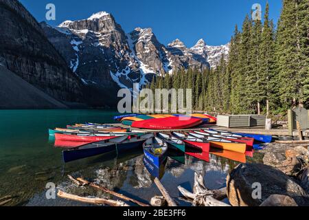 Colorful canoes docked in the turquoise waters of Lake Louise and the snow dusted Fairview Mountain behind in Banff National Park in Alberta, Canada. Stock Photo