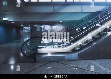Contemporary glass and chrome escalator in a hall of subway or shopping mall, or an airport terminal, or a railway station depot with a small passage Stock Photo