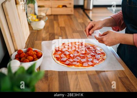 Woman preparing a traditional Italian pizza. The original process of making pizza. Stock Photo