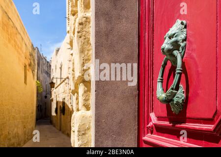 Door knocker on red door, walled city of Mdina, Malta Stock Photo