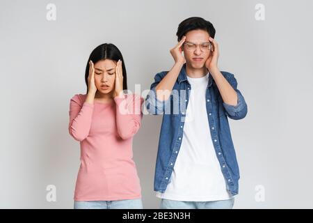 Asian sad couple having headache, touching their temples Stock Photo