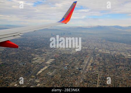 Southwest Airlines Boeing 737 flying over LA suburbs with Los Angeles Skyline in background en route to Los Angeles International Airport. Stock Photo