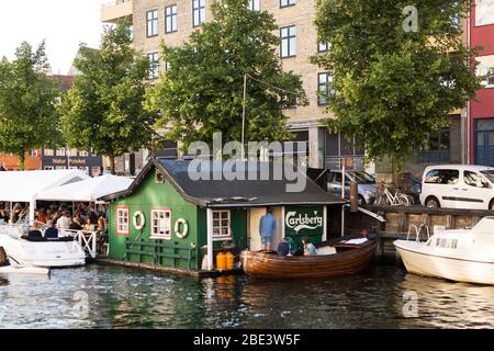 The Christianshavn boat rental and café draws a crowd to a canal on Overgaden Neden Vandet on a summer evening in Copenhagen, Denmark. Stock Photo