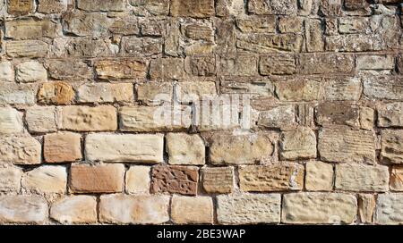 old yellow and brown sandstone wall made of blocks of irregular shape  background Stock Photo