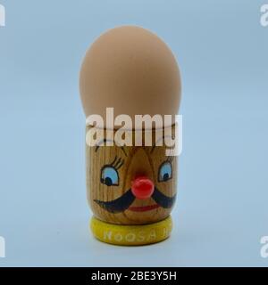 Retro style wooden Japanese egg cup with a boiled egg and funny mustache man's face on it with a red nose from Noosa Heads in the 1960s in Australia Stock Photo