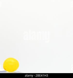 April 2020, Close Up Of A Small Round Yellow Candy On A White Background, London, England. Stock Photo
