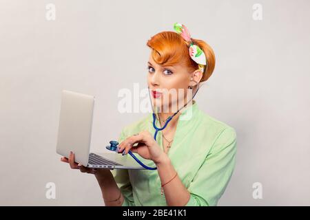 Surprised pinup girl listening computer with stethoscope looking at you retro vintage hairstyle Healthcare diagnosis software repair diagnostics inter Stock Photo