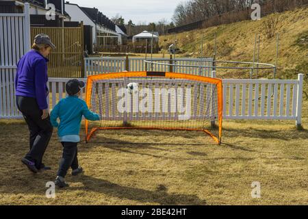 Stay at home. Outdoor games. Grandma with grandson playing football on backyard. Covid-19. Stock Photo