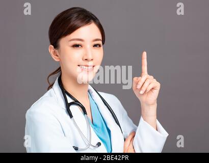 Smiling asian female doctor hand point up Stock Photo