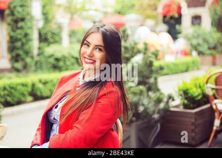 Relaxing woman sitting outside comfortable on a terrace balcony. Resting beautiful young multicultural asian indian caucasian girl in her 20s . Stock Photo