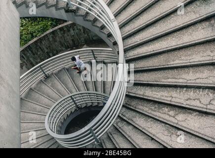 Abstract Street Photography of Man Walking Down Spiral Stairs in Hong Kong Stock Photo