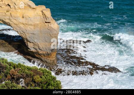 Coastal natural arch viewed from adjacent cliffs with waves crashing around on Great Ocean Road, Victoria in Australia. Stock Photo