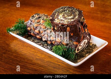 Close-up of decorative log cake with pine needle trimmings on a wooden table; Studio Stock Photo