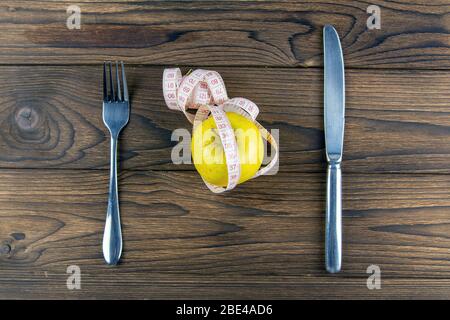 Diet. Dieting Concept. Diet Menu. Apple with measure tape, knife and fork. Diet food on wooden table. Top views Stock Photo