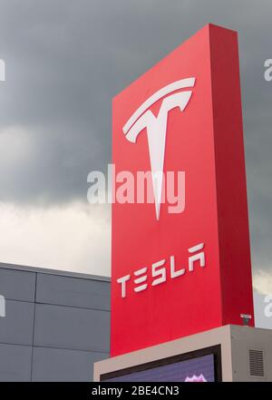 Electric car company's red and white logo sign outside Tesla Tysons Corner-Tyco Road store, Vienna, Virginia, USA, with cumulonimbus storm cloud above Stock Photo