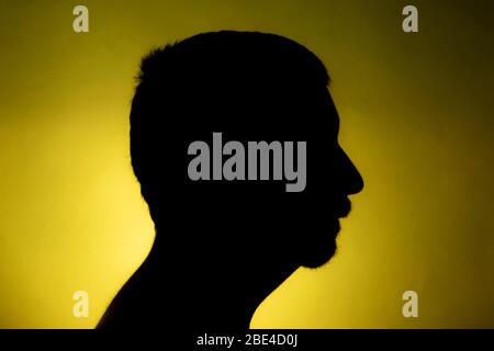 Cleanly defined silhouette of a male person against a red background with a  spotlight and bright area right behind the bust. Studio shot profile Stock  Photo - Alamy