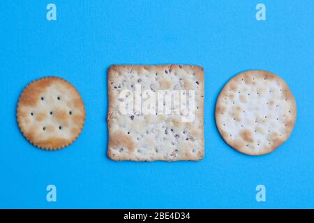 Round and square salted crackers on blue background - top view with copy space Stock Photo