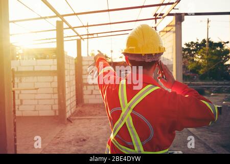 Engineer wear a hard hellmet and using smartphone  at construction site Stock Photo