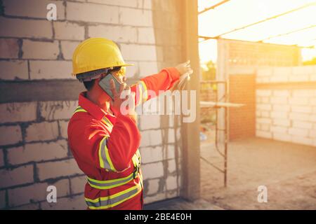 Engineer wear a hard hellmet and using smartphone  at construction site Stock Photo