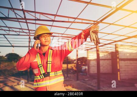 Engineer wear a hard hellmet and using smartphone  at construction site Stock Photo