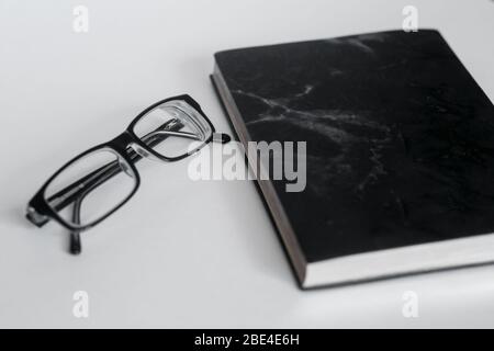 New black leather Notebook diary with black glasses isolated on white background Stock Photo