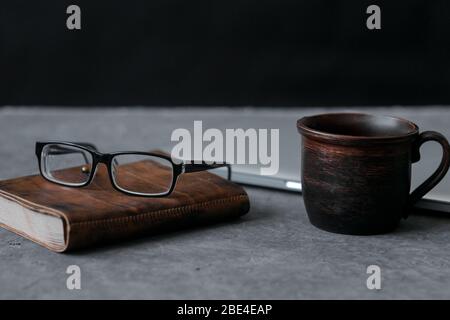 Brown leather notebook, pen, laptop and glasses on gray background. Stock Photo