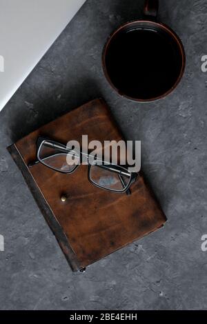 Brown leather notebook, pen, laptop and glasses on gray background. Stock Photo