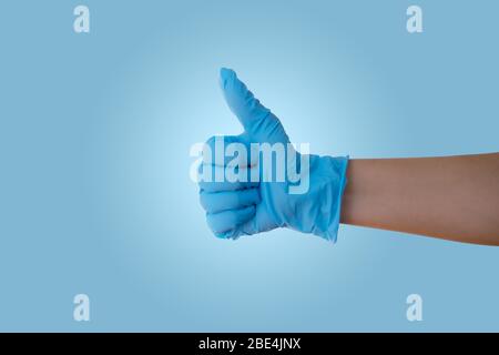 Hand with blue latex medical glove with thumb up showing OK sign Stock Photo