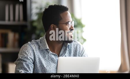 Happy young mixed race man distracted from job, looking aside. Stock Photo