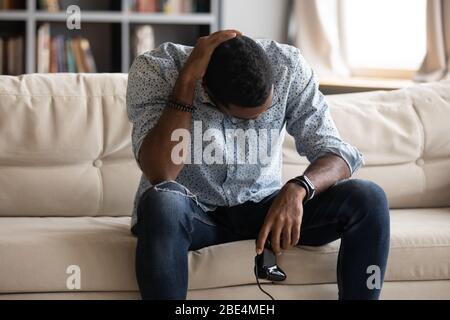 Unhappy young biracial man feeling upset after loosing xbox game. Stock Photo