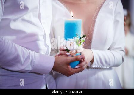 Burning candle in the hands of the newlyweds Stock Photo