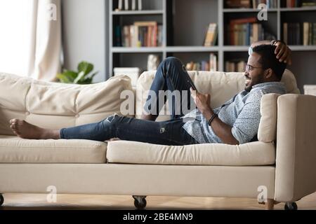 Relaxed young african ethnicity man using mobile phone. Stock Photo