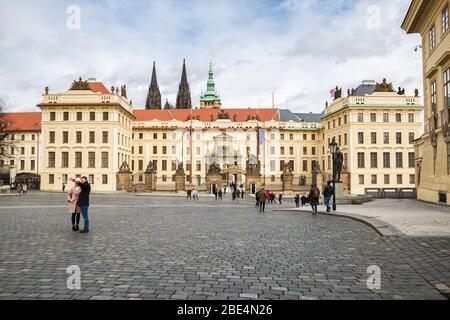 PRAGUE, CZECH REPUBLIC - MARCH 10, 2020: Hradcanske Square, Prague Castle and new Royal Palace. Tourists take selfies against background of  sights Stock Photo